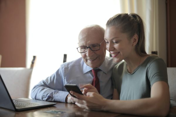 Older man and younger woman helping on phone