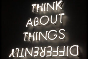 Neon sign that says think about things differently